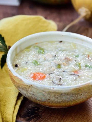 Korean porridge made with leftover turkey in a brown ceramic bowl