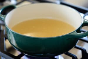 Boiling chicken broth in a green pot to make dumpling soup