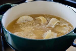 Boiling Korean dumplings in chicken broth in a green pot