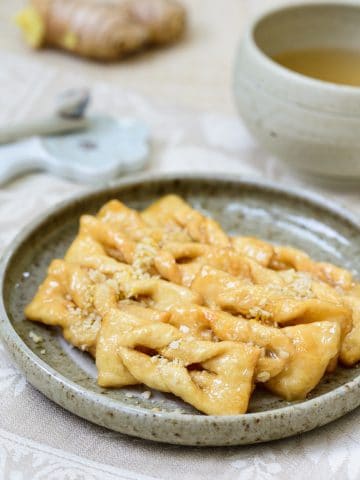 Korean twisted ginger cookies topped with chopped pine nuts with a cup of tea