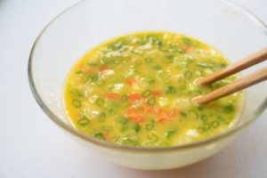 Mixing the chopped vegetables to the beaten eggs