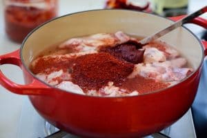 Chicken cut up in a pot with gochugaru and gochujang