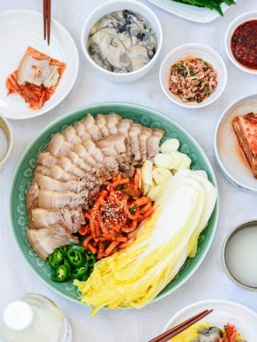 Boiled and sliced pork belly served with salted napa cabbage and spicy radish salad with kimchi, oysters and sauce