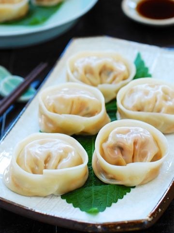 5 Kimchi dumplings on a square plate with a dipping sauce