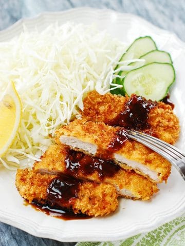 Sliced Pork cutlet served with shredded cabbage and sliced cucumber with lemon slice