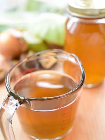 Vegetable broth in a jar and a measuring cup